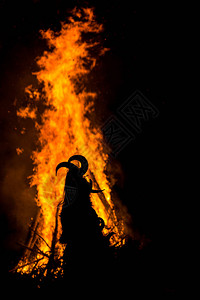 戴着大角的可怕面具的男子在巨大的仪式火前跳舞图片