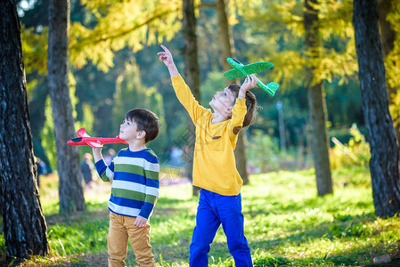快乐的两个兄弟孩子在蓝色的夏日天空背景下玩具飞机男孩们在森林或公园里扔泡沫飞机最图片