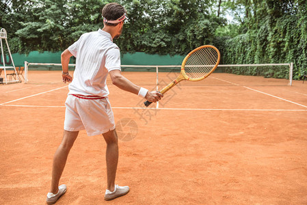 网球场上带复古木制球拍的网球运动员的背影图片