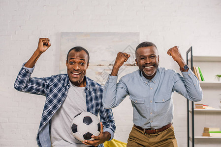 快乐的父亲和成年儿子足球比赛胜利笑着图片