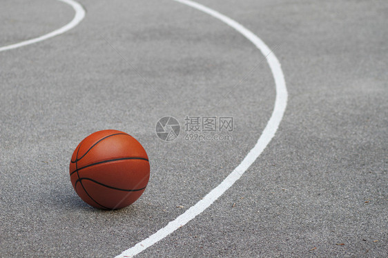 位于沥青地板上的孤立橙色篮球图片