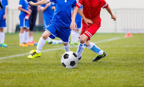年轻足球运动员踢足球男孩在体育场踢足背景图片