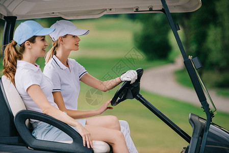 戴帽子的女高尔夫球手在高尔夫球场骑高尔夫图片
