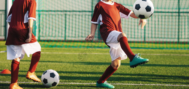 男孩练习足球年轻的足球运动员在球场上踢球儿童图片