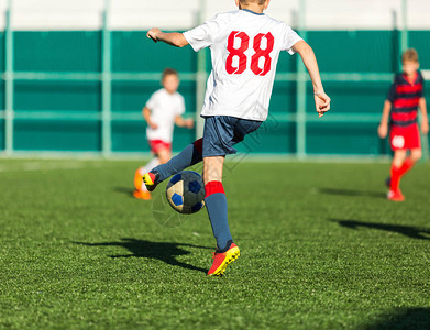 穿着红色白运动服的男孩在足球场上奔跑年轻的足球运动员在比赛中运球和踢足球训练积极生活方式运动图片