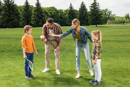 父母教小孩子如何在草坪上打羽毛球图片
