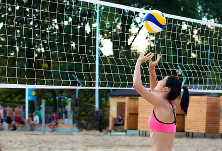 浅色黑发女人在海滩上网边玩排球图片
