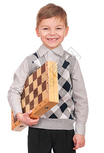 白种人小男孩的情感画象有棋枰的有趣的孩子一边笑一边怀里抱着一盘棋可爱聪明的孩子图片