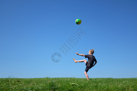 小男孩在草地上踢球图片