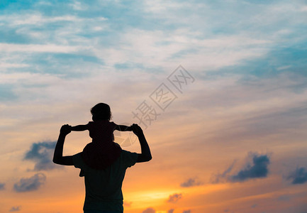 父亲和小女儿的剪影在夕阳的天空中玩耍图片