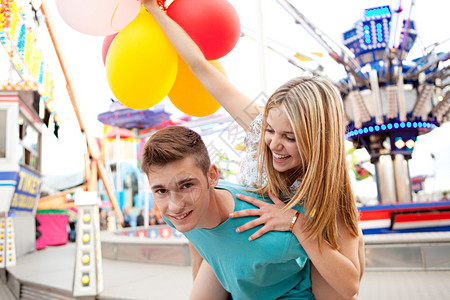 快乐的年轻夫妇在参观带有游乐设施的景点公园拱廊时嬉戏图片