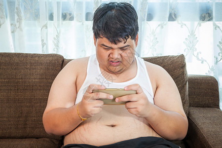 亚洲胖子用智能手机玩游戏图片