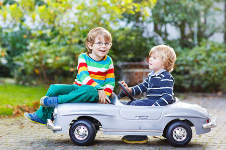 两个快乐的孩子在夏日花园户外玩大老玩具车在温暖的一天图片