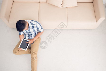 坐在地板上的人用数字平板电脑图片