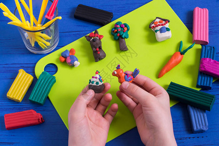 孩子手里拿着鸟和橡皮泥蛋糕儿童的艺术创造力儿童艺术工艺品的彩色橡皮泥桌上的现成玩具幼儿园和家图片