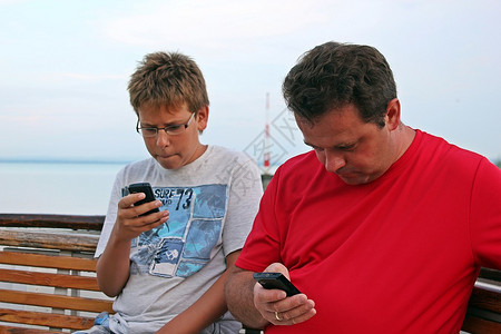 男人和男孩的手机坐在图片