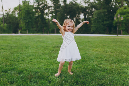 微笑的小可爱小女孩穿着轻便的衣服走路和伸展双手图片