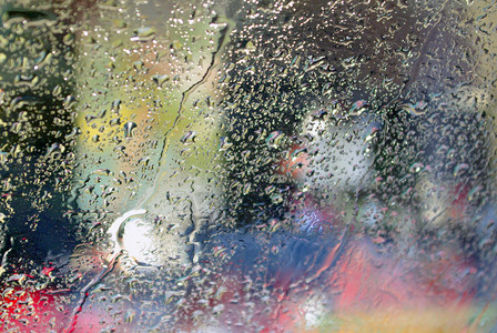 汽车挡风玻璃上有雨滴的彩色背景图片
