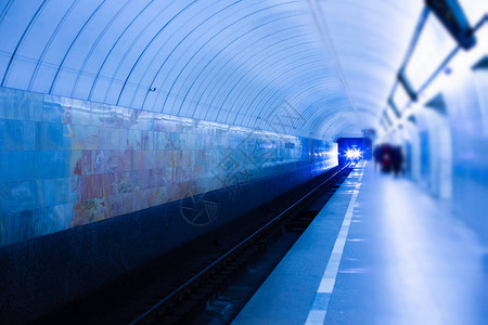 一列火车的两个前灯从地铁隧道的黑暗中抵达地下站台夜蓝色灯光下的地铁图片