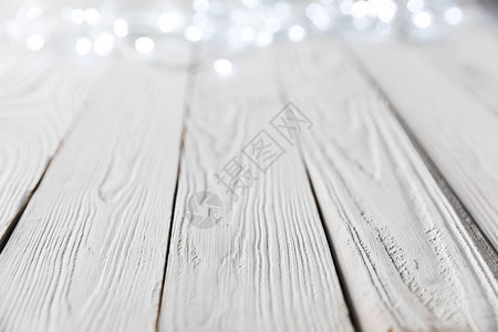 白色木质表面上的节日圣诞散景灯图片