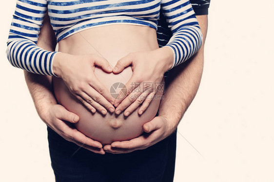 有心脏标志的怀孕的腹部男人拥抱孕妇和女人手牵着手在她的肿块上呈心形父图片