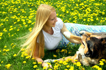 一个迷人的年轻女人和她的德国牧羊人Mix狗躺在外面图片