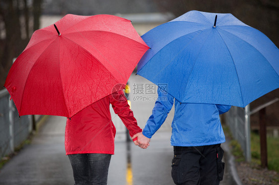 一对夫妇手牵在雨中行走带图片