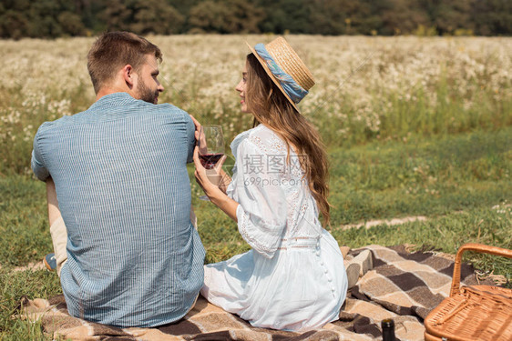 看到一对微笑的情侣在夏日草原上野餐图片