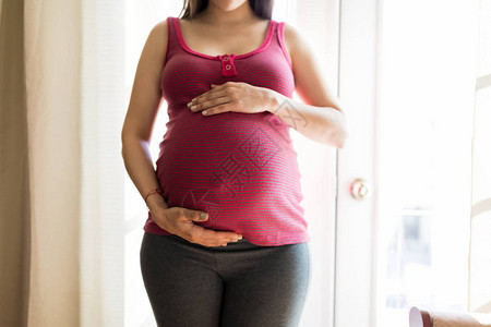 中产孕妇在家中抚摸肚子以感受胎儿运动图片