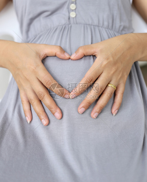 孕妇将他的手放在她肚子上的心脏形状感受图片