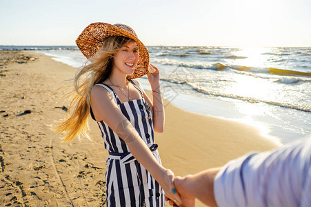 在沙滩上行走时微笑着的女人手握着男友图片