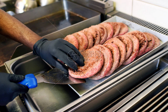 厨师在快餐店里用垃圾袋把一个金属托盘上的牛肉卷拿了个预先图片