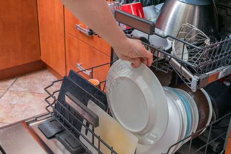 女手在洗碗机里给脏盘子图片