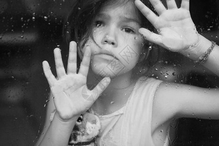 孤独悲伤的年轻前女孩在窗上握着手掌图片