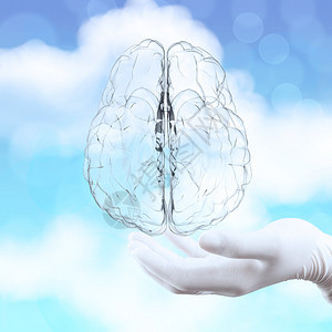 医生手把3D玻璃人的大脑显示在自然背景上作图片