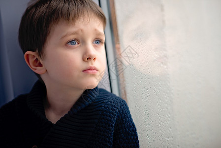 儿童在窗边等雨停孤独和等待的概念图片