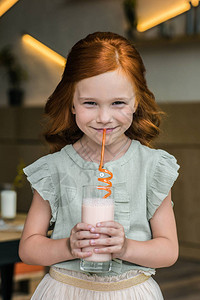 可爱的红发女孩用稻草喝奶昔图片
