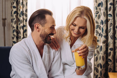 在浴袍中快乐的中年情侣在酒店房间图片