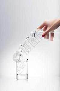 妇女用塑料瓶子倒入玻璃图片