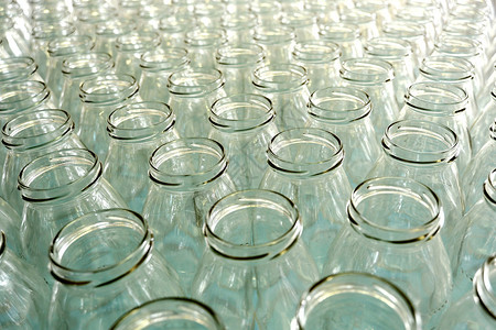 在装瓶厂工厂的生产线上或在商店出售的多排没有盖的透明空玻璃瓶图片