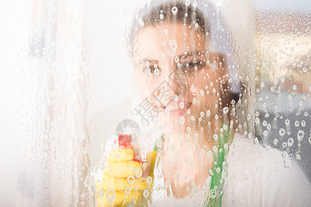 女清洁女工或家庭主妇用喷雾洗窗图片