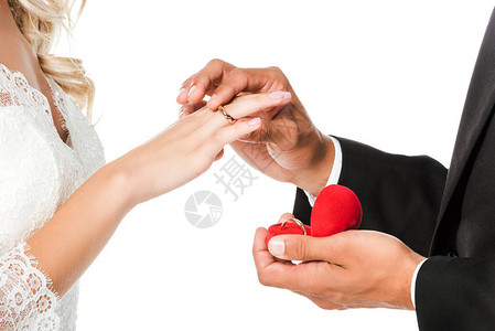 新郎在新娘的手指上戴结婚戒指图片