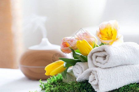 带有现代精油扩散器香气的水疗组合物和身体护理产品扭曲的白毛巾春天的绿色和鲜花身体和保背景图片
