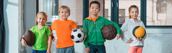 在体育馆一起微笑全景镜头中观看的多文化儿童的球和笑容图片