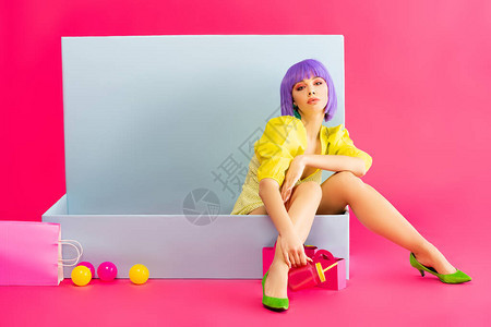 紫色假发的女孩像洋娃坐在蓝色盒子里图片
