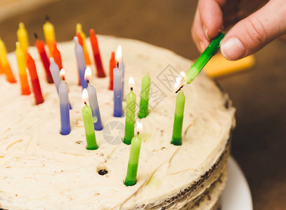 在生日蛋糕上点燃彩色蜡烛的人图片