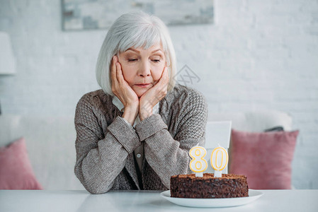 坐在桌边的年老女士生日蛋糕家背景图片