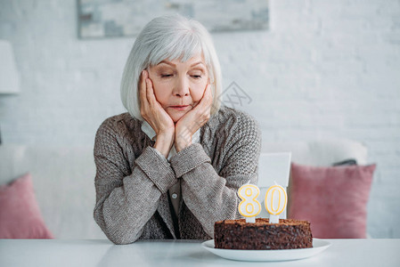 坐在桌边的年老女士生日蛋糕家图片