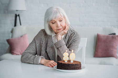 坐在桌边的年老女士生日蛋糕家背景图片