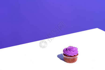 带有紫色奶油釉的纸杯蛋糕白色表面图片